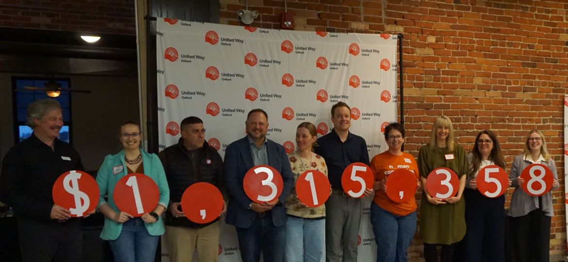Group of event attendees stand holding numbers that make the number $1,315,358
